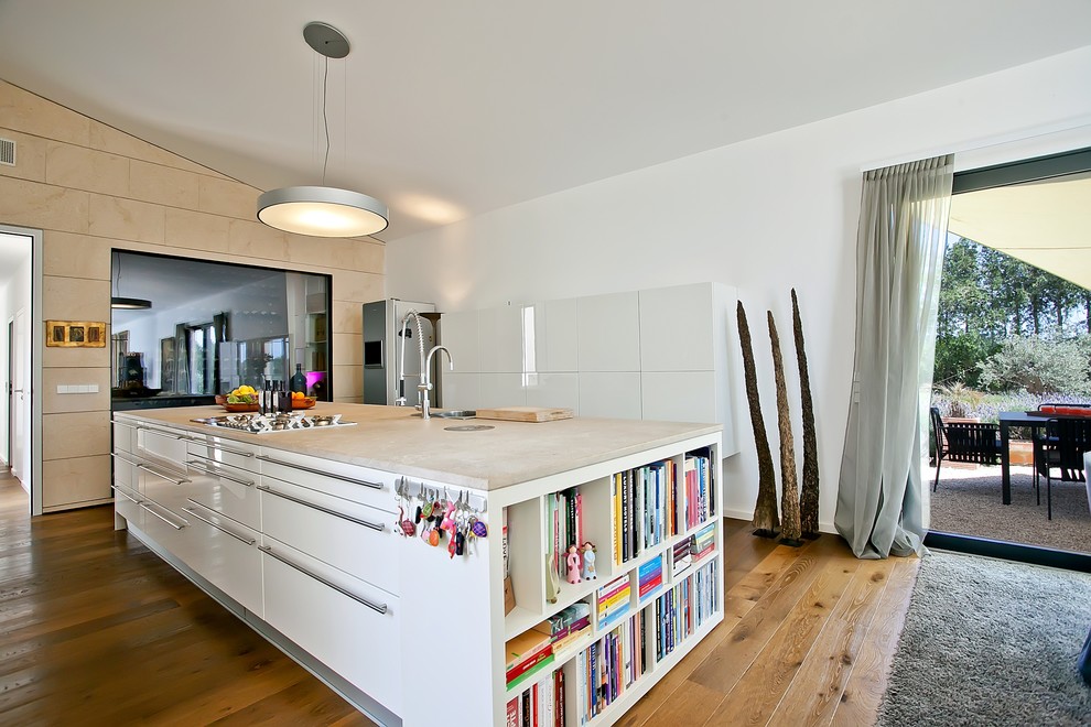 Modelo de cocina comedor contemporánea con puertas de armario blancas, fregadero encastrado, armarios con paneles lisos, suelo de madera en tonos medios y una isla