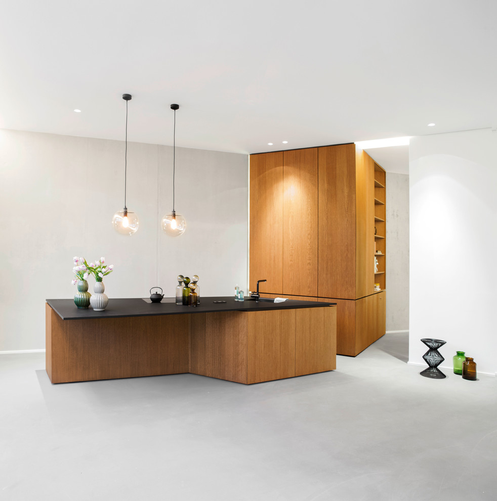 Mittelgroße Moderne Küche mit flächenbündigen Schrankfronten, hellbraunen Holzschränken, Betonboden, Kücheninsel und grauem Boden in Berlin