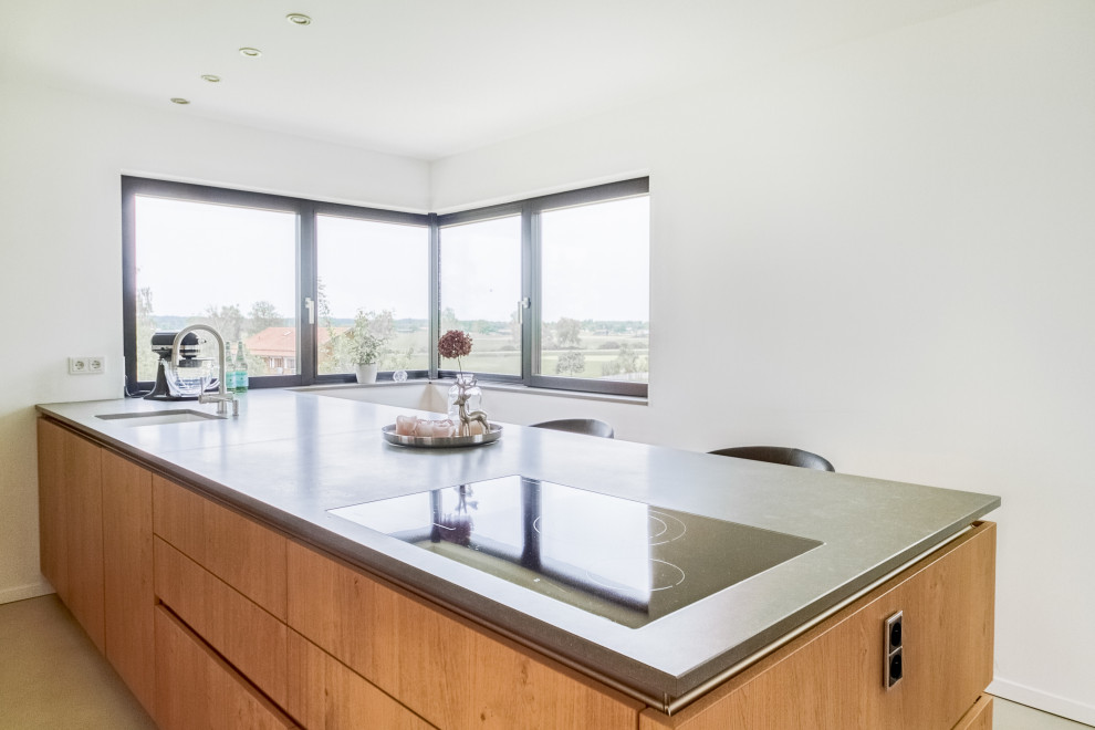 Zweizeilige Moderne Wohnküche mit Unterbauwaschbecken, offenen Schränken, hellbraunen Holzschränken, Halbinsel und grauer Arbeitsplatte in München