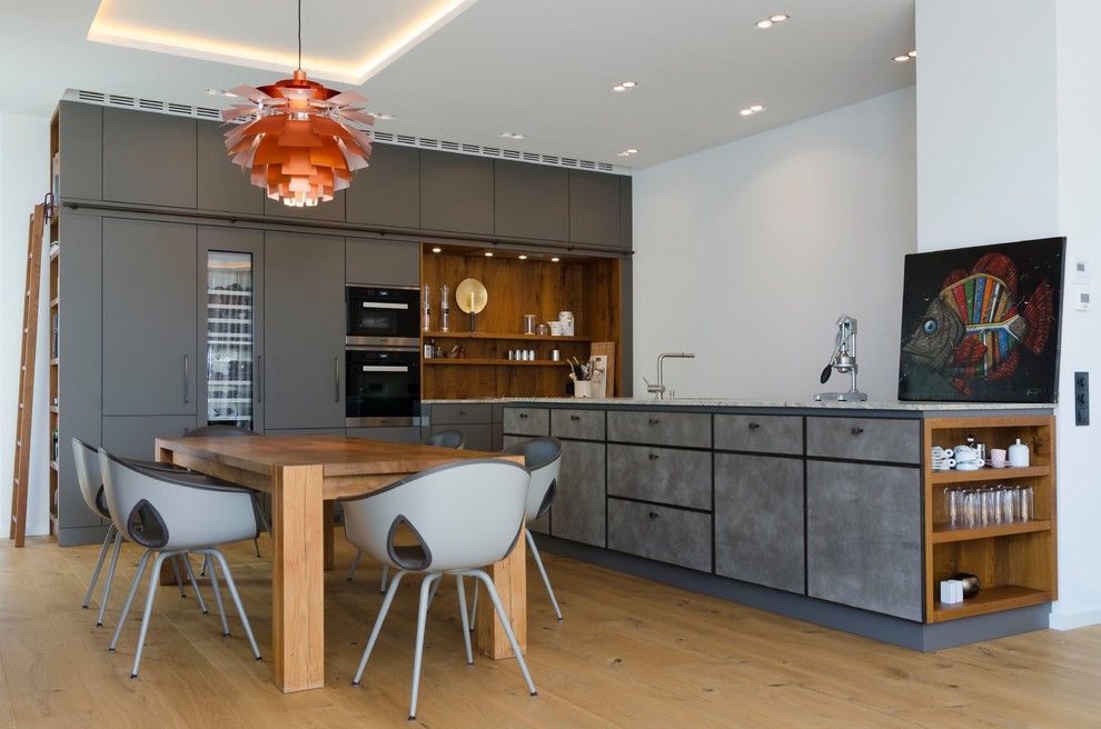 Idéer för att renovera ett stort funkis kök, med släta luckor, svarta vitvaror, mellanmörkt trägolv, grå skåp, marmorbänkskiva och brunt golv