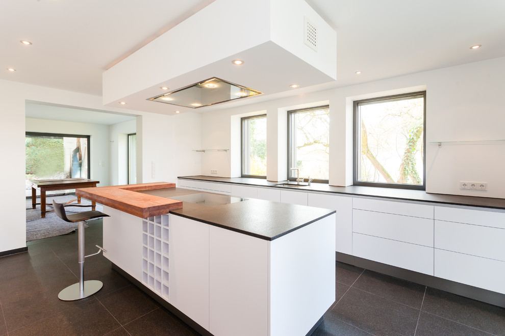 Modern inredning av ett stort kök, med släta luckor, vita skåp, en köksö och en undermonterad diskho