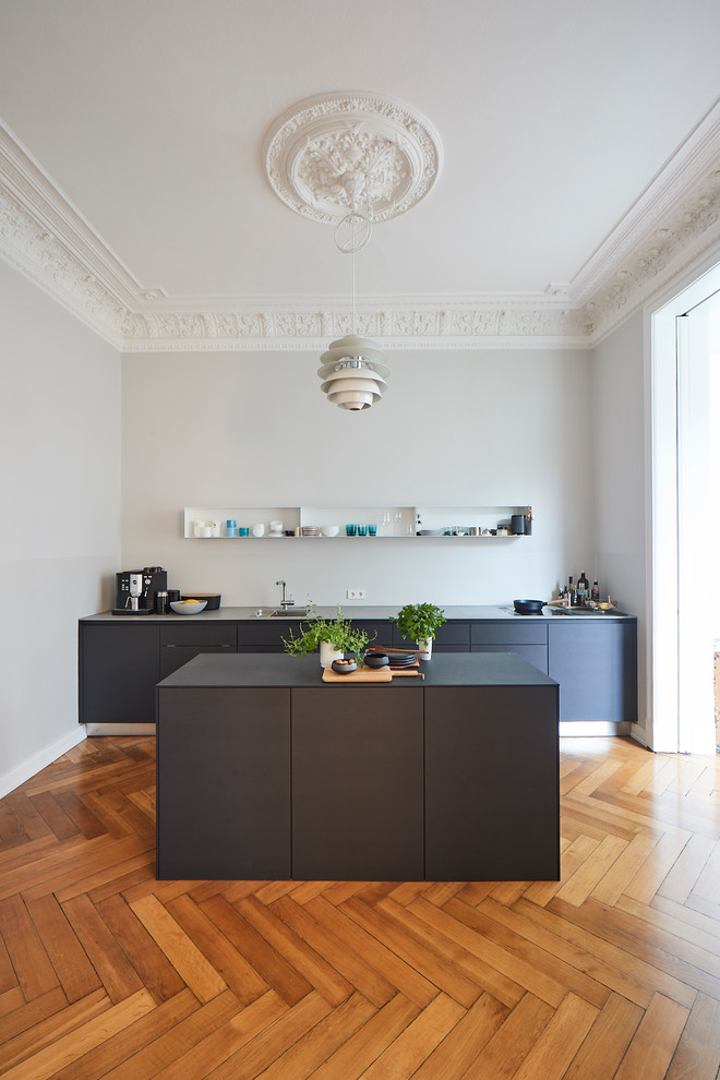 Inspiration for a large traditional single-wall open plan kitchen in Hamburg with a built-in sink, flat-panel cabinets, grey cabinets, wood worktops, grey splashback, painted wood flooring, an island, brown floors and grey worktops.