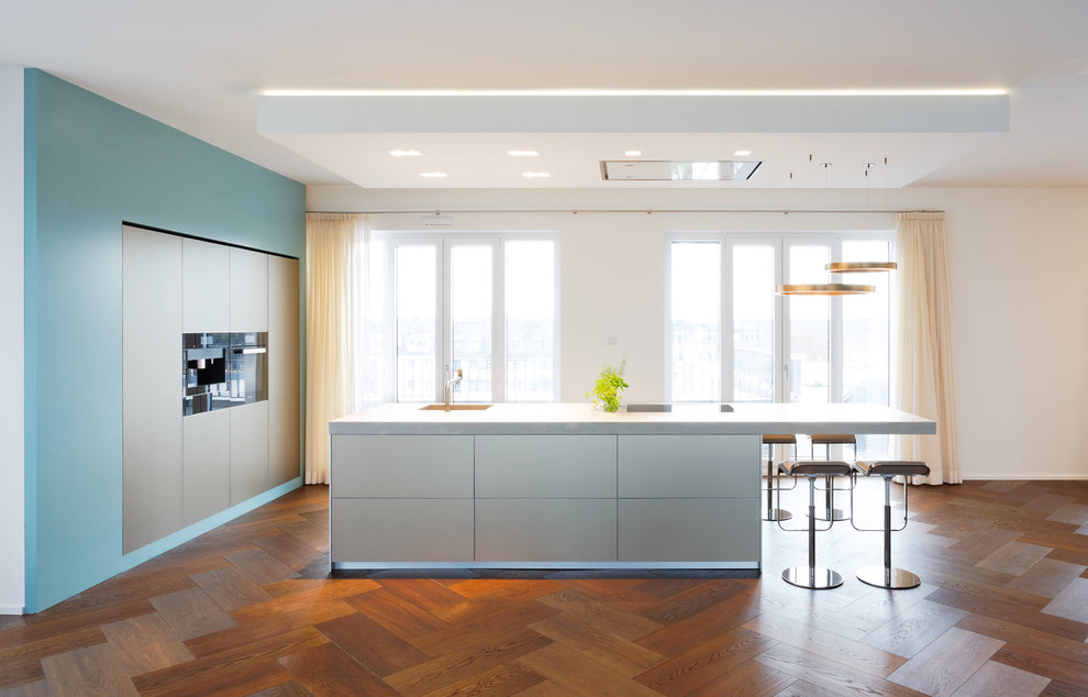 Esempio di una cucina moderna di medie dimensioni con lavello integrato, ante lisce, ante beige, top in cemento, elettrodomestici neri e parquet scuro
