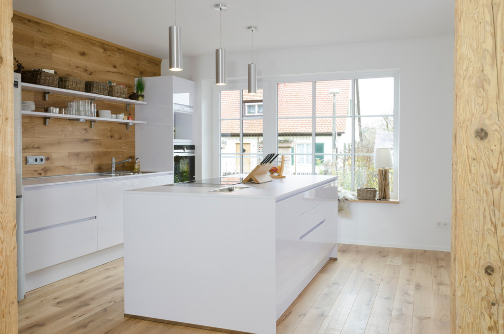 Modern inredning av ett avskilt, stort linjärt kök, med en nedsänkt diskho, släta luckor, vita skåp, rostfria vitvaror, mellanmörkt trägolv och en köksö