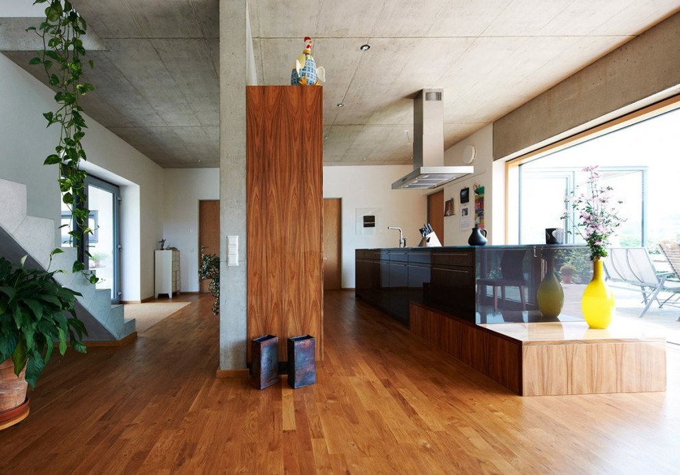 Idée de décoration pour une grande cuisine ouverte design avec un placard à porte plane, des portes de placard noires, un sol en bois brun et îlot.