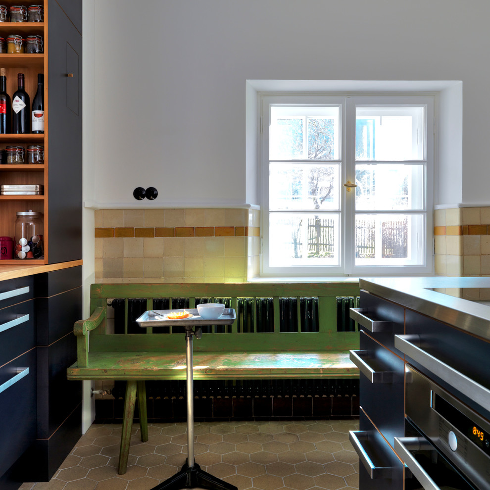 Shabby-Look Küche mit flächenbündigen Schrankfronten, schwarzen Schränken und Edelstahl-Arbeitsplatte in München