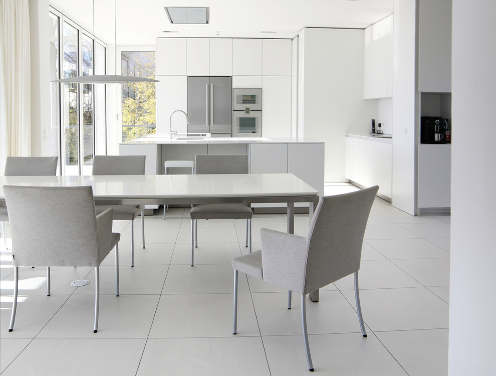Medium sized contemporary grey and white open plan kitchen in Stuttgart with a single-bowl sink, flat-panel cabinets, white cabinets, stainless steel appliances and an island.