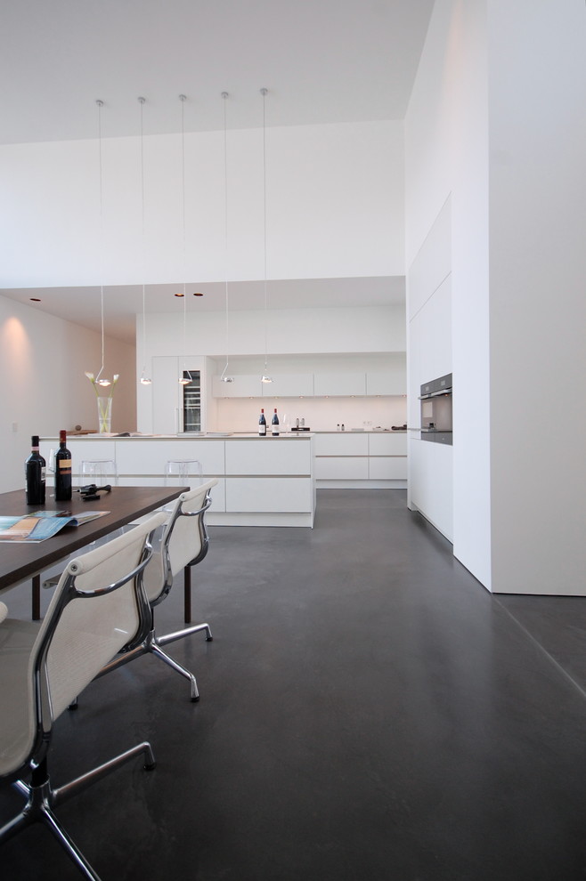 Offene, Große Moderne Küche mit flächenbündigen Schrankfronten, weißen Schränken, Küchenrückwand in Weiß und Kücheninsel in Köln