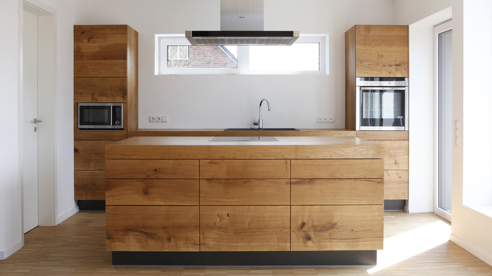 Immagine di una cucina design di medie dimensioni con lavello da incasso, ante lisce, ante in legno scuro, top in legno, parquet chiaro, elettrodomestici da incasso e pavimento marrone