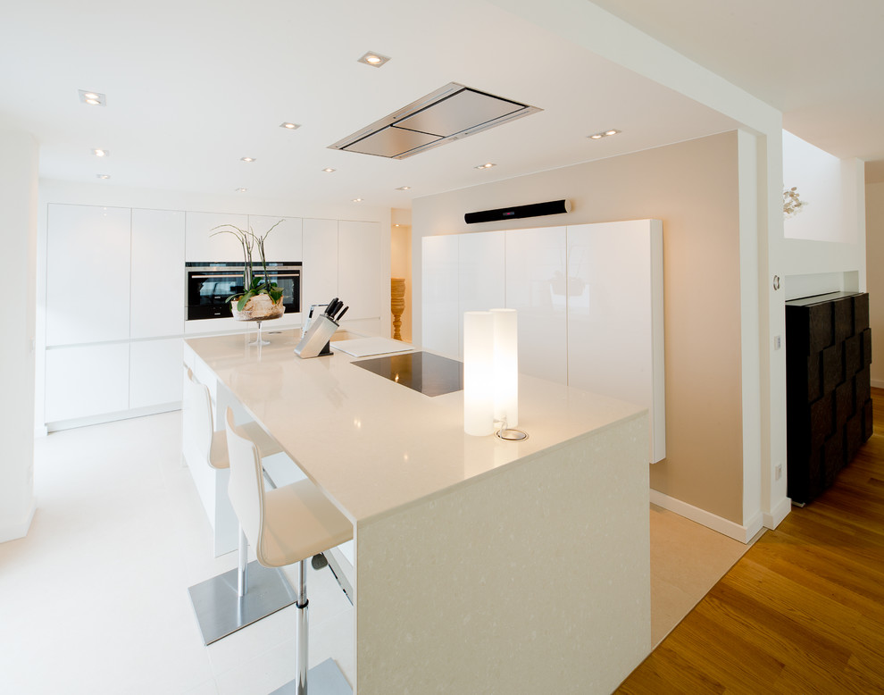 Diseño de cocina contemporánea grande abierta con puertas de armario blancas, armarios con paneles lisos, una isla, fregadero bajoencimera y electrodomésticos con paneles