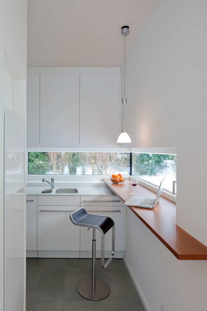 На фото: отдельная кухня среднего размера в современном стиле с плоскими фасадами, белыми фасадами и врезной мойкой без острова