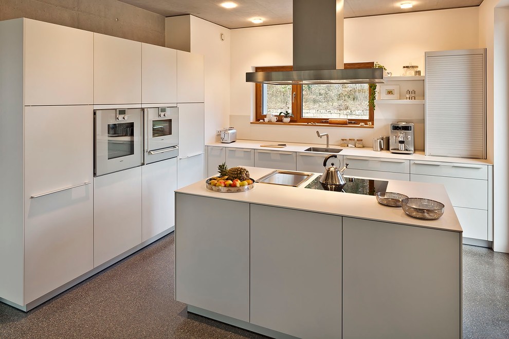 Ejemplo de cocinas en L contemporánea de tamaño medio cerrada con fregadero bajoencimera, armarios con paneles lisos, puertas de armario blancas, electrodomésticos con paneles, una isla y salpicadero verde