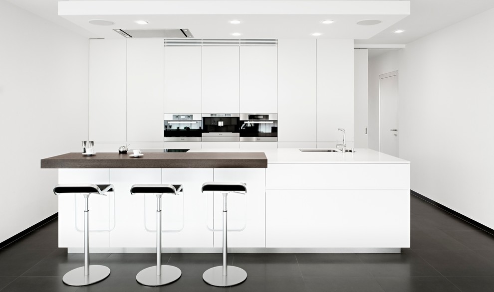 Moderne Küche mit flächenbündigen Schrankfronten, Küchenrückwand in Weiß und Kücheninsel in Sonstige