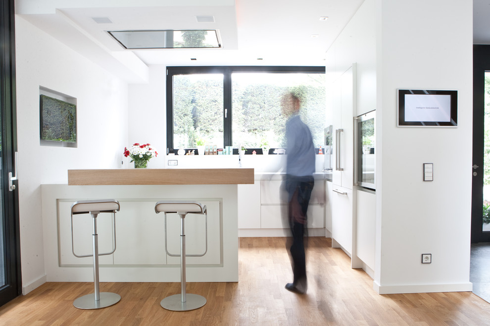 Offene Moderne Küche in U-Form mit weißen Schränken, Küchenrückwand in Weiß und Halbinsel in Düsseldorf