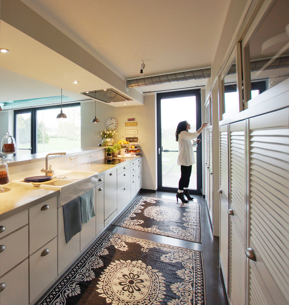 Foto de cocina abierta sin isla con armarios con puertas mallorquinas, puertas de armario con efecto envejecido, suelo de cemento y suelo negro