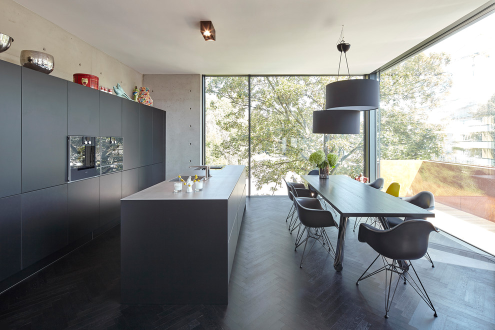 Пример оригинального дизайна: параллельная кухня среднего размера в современном стиле с обеденным столом, плоскими фасадами, черными фасадами, черной техникой, темным паркетным полом, двумя и более островами, черным полом и черной столешницей