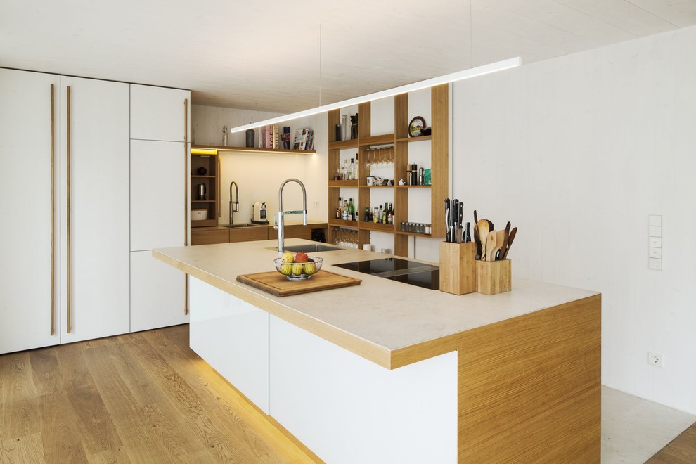 Exempel på ett stort modernt kök med öppen planlösning, med en enkel diskho, öppna hyllor, skåp i ljust trä, integrerade vitvaror, ljust trägolv, en köksö och vitt stänkskydd