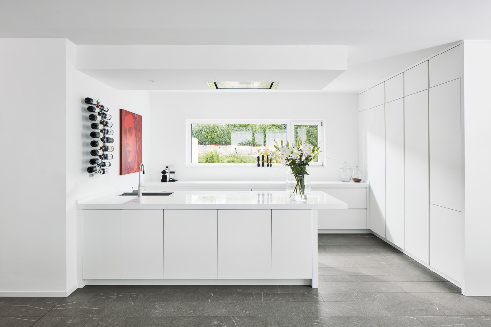 Idéer för att renovera ett stort funkis vit vitt u-kök, med en undermonterad diskho, släta luckor, vita skåp, integrerade vitvaror, en halv köksö och grått golv