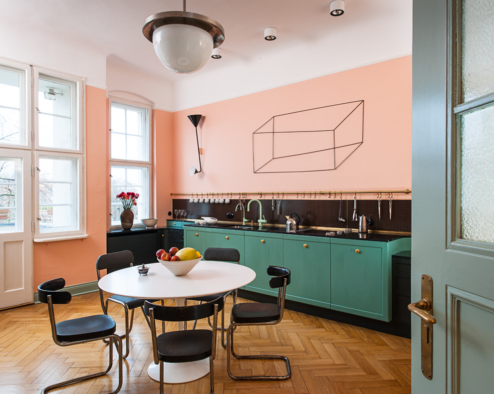 Пример оригинального дизайна: большая прямая кухня в современном стиле с обеденным столом, врезной мойкой, плоскими фасадами, зелеными фасадами, черным фартуком и паркетным полом среднего тона без острова
