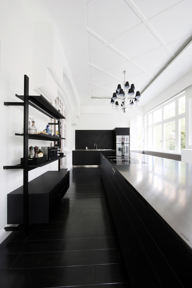 Exempel på ett modernt kök med öppen planlösning, med en integrerad diskho, släta luckor, svarta skåp, bänkskiva i rostfritt stål, svart stänkskydd, rostfria vitvaror och en köksö