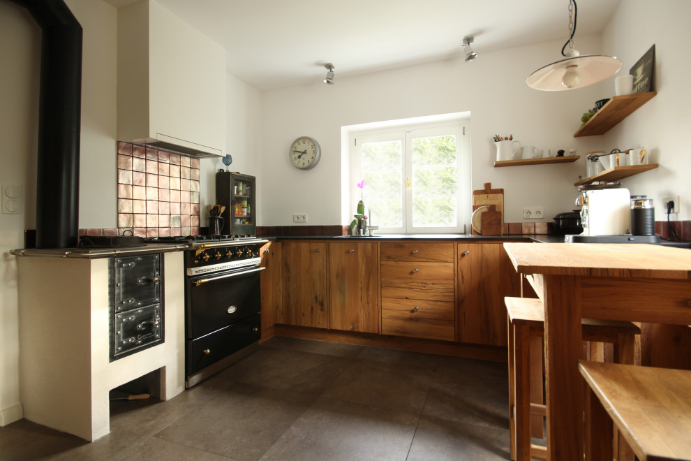 This is an example of a medium sized rustic u-shaped kitchen/diner in Munich with a submerged sink, dark wood cabinets, granite worktops, black appliances, no island, grey floors and black worktops.