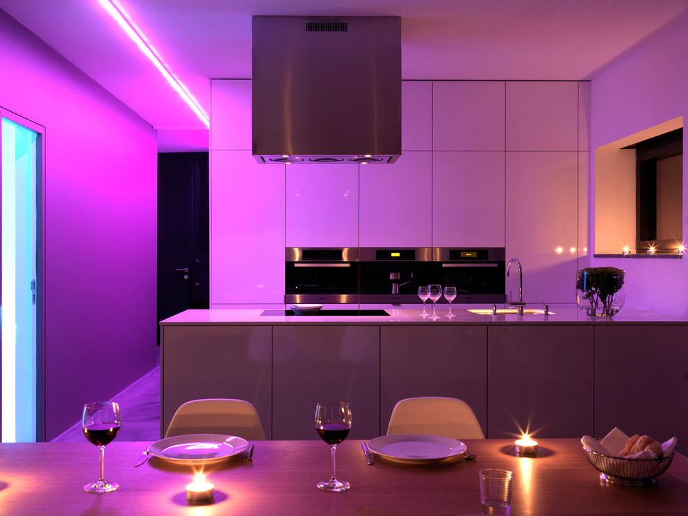 Photo of a large contemporary grey and purple open plan kitchen in Stuttgart with flat-panel cabinets, white cabinets, stainless steel appliances, a breakfast bar and a submerged sink.