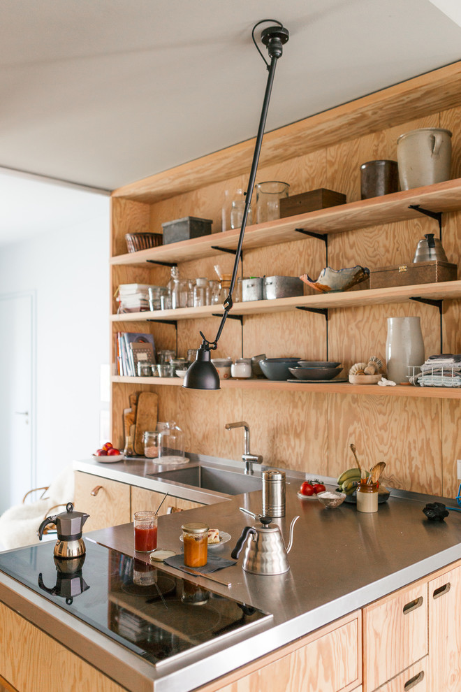 Aménagement d'une cuisine ouverte scandinave de taille moyenne avec un évier intégré, un placard à porte plane, des portes de placard marrons, un plan de travail en inox, une crédence marron et un électroménager en acier inoxydable.