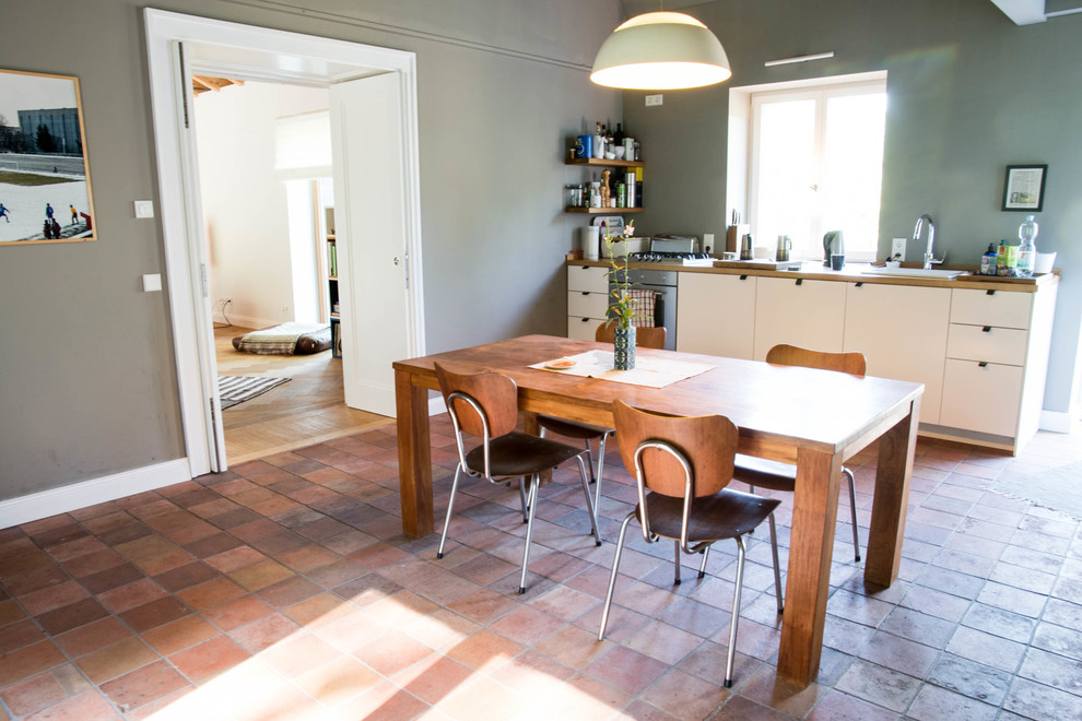 Exempel på ett stort skandinaviskt linjärt kök och matrum, med en nedsänkt diskho, släta luckor, vita skåp, träbänkskiva, rostfria vitvaror och klinkergolv i terrakotta