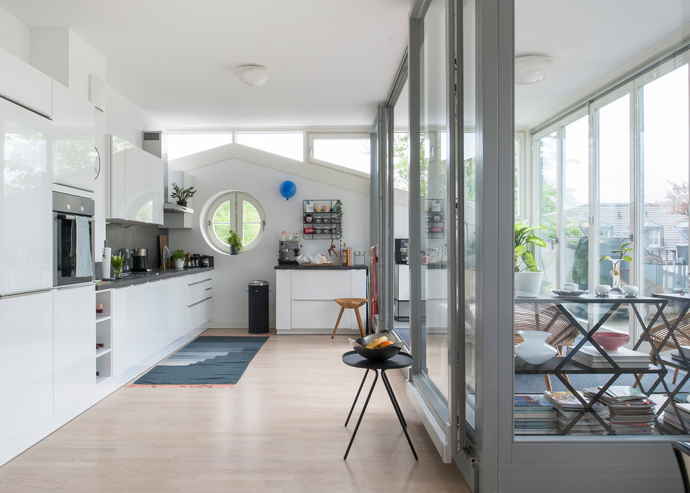 Moderne Küche mit flächenbündigen Schrankfronten, Küchengeräten aus Edelstahl und hellem Holzboden in Berlin