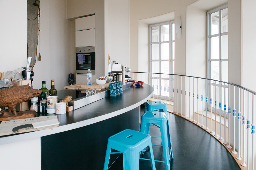 Kleine Eklektische Wohnküche mit flächenbündigen Schrankfronten, weißen Schränken und Küchengeräten aus Edelstahl in Berlin