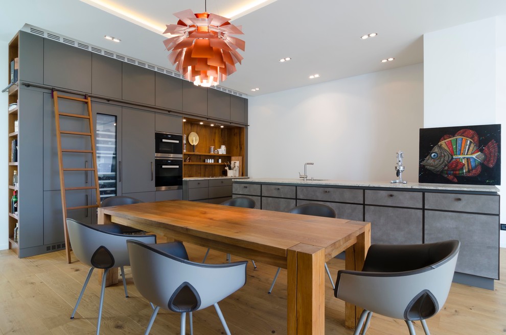 Offene, Große Moderne Küche in L-Form mit flächenbündigen Schrankfronten, grauen Schränken, hellem Holzboden und Halbinsel in Hamburg