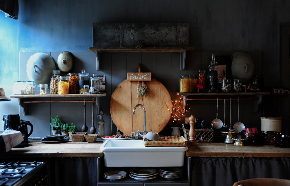 Kleine Country Küche mit Landhausspüle, Küchenrückwand in Blau, Rückwand aus Keramikfliesen, Arbeitsplatte aus Holz und Mauersteinen in Düsseldorf