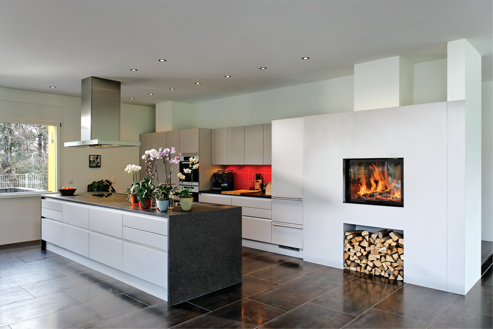 Foto på ett stort funkis linjärt kök med öppen planlösning, med en nedsänkt diskho, släta luckor, vita skåp, rött stänkskydd, integrerade vitvaror och en köksö