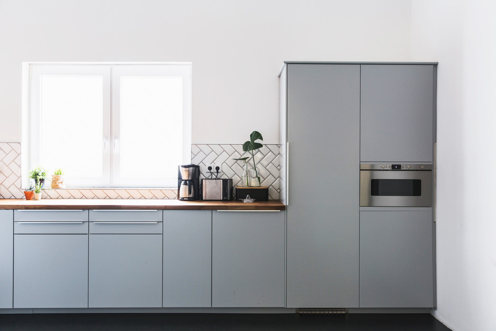Idéer för mellanstora skandinaviska kök med öppen planlösning, med en rustik diskho, grå skåp, träbänkskiva, vitt stänkskydd, stänkskydd i keramik, rostfria vitvaror och betonggolv