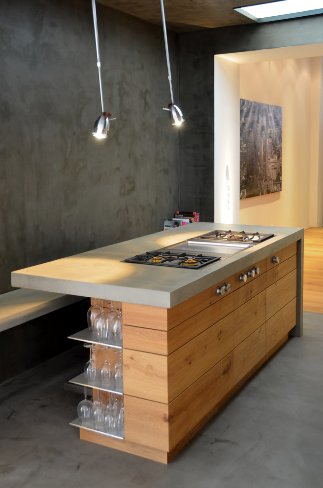 Kleine Moderne Küche mit flächenbündigen Schrankfronten, hellbraunen Holzschränken, Betonarbeitsplatte, Elektrogeräten mit Frontblende und Kücheninsel in Köln