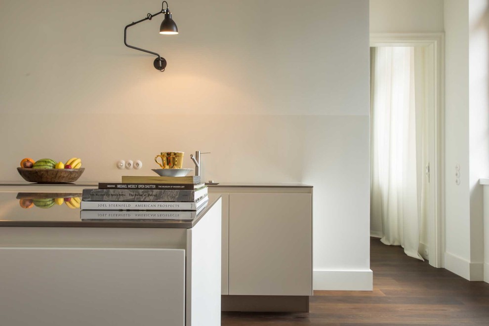 Offene, Zweizeilige Moderne Küche mit profilierten Schrankfronten, weißen Schränken, Edelstahl-Arbeitsplatte, Küchenrückwand in Weiß, gebeiztem Holzboden und zwei Kücheninseln in Berlin