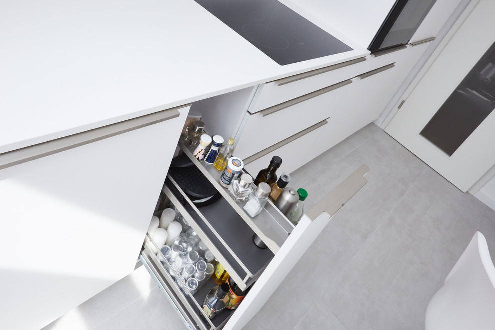 Idéer för avskilda, mellanstora funkis linjära vitt kök, med en undermonterad diskho, vita skåp, bänkskiva i kvarts, vitt stänkskydd, glaspanel som stänkskydd och svarta vitvaror