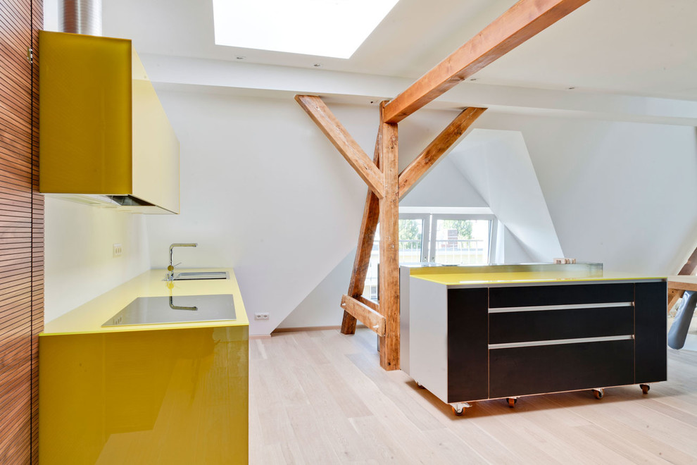 Imagen de cocina lineal pequeña abierta con fregadero encastrado, armarios con paneles lisos, puertas de armario amarillas, salpicadero blanco y suelo de madera clara