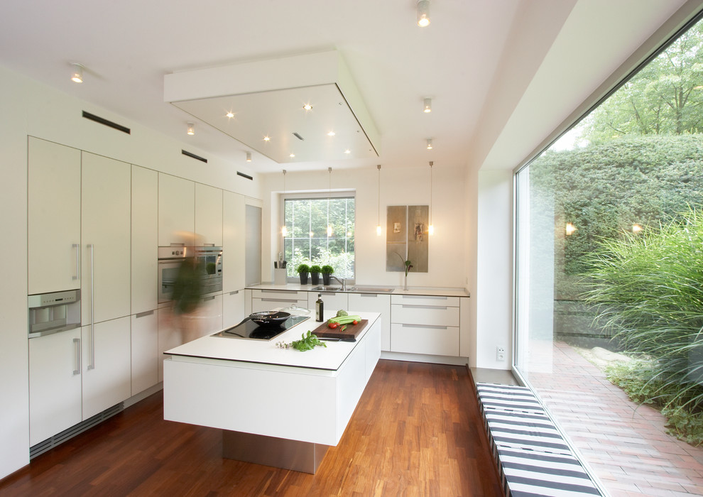Medium sized contemporary l-shaped enclosed kitchen in Hamburg with a double-bowl sink, flat-panel cabinets, white cabinets, integrated appliances, medium hardwood flooring, an island and brown floors.