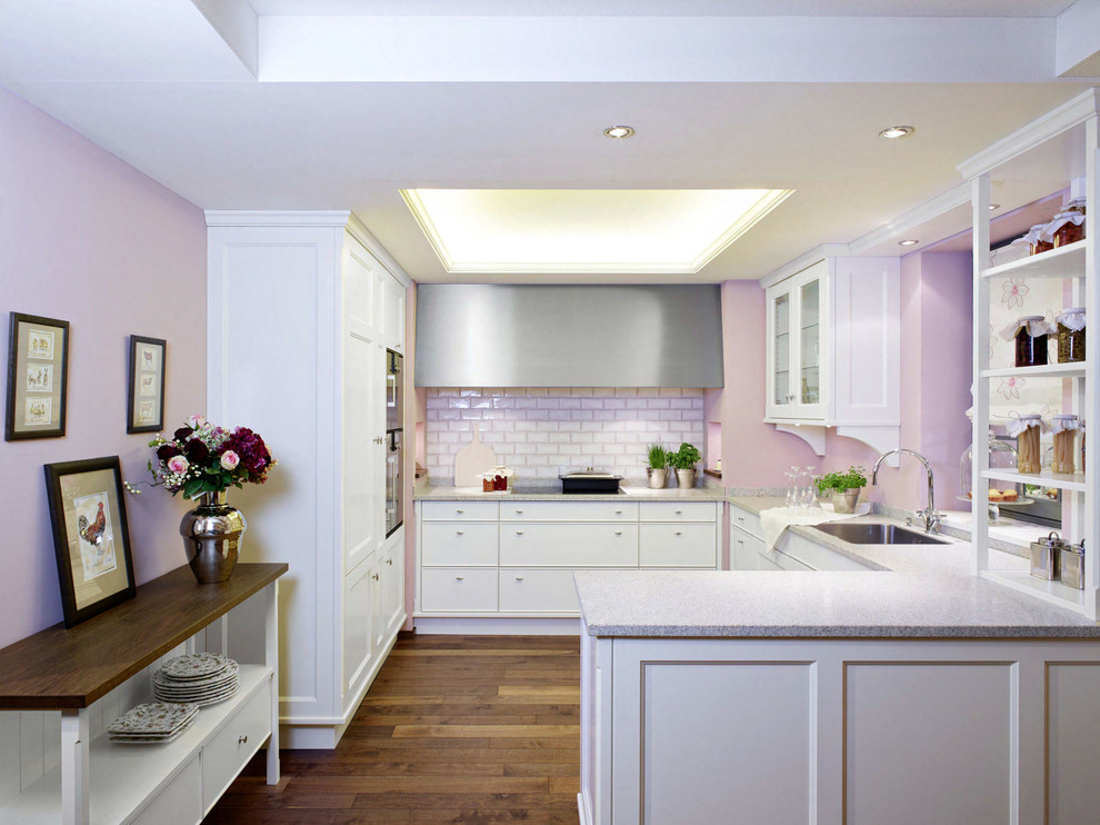 Bild på ett mellanstort lantligt kök, med en nedsänkt diskho, luckor med infälld panel, vita skåp, granitbänkskiva, rostfria vitvaror, mellanmörkt trägolv och brunt golv