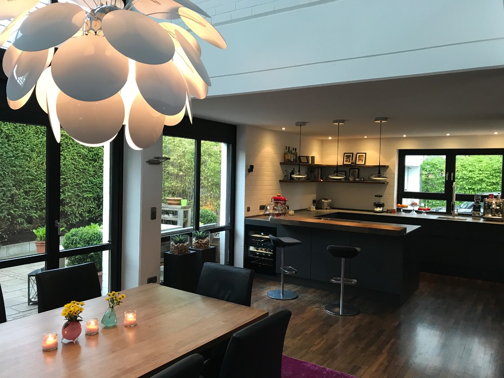 Photo of a large urban u-shaped kitchen/diner in Other with an integrated sink, flat-panel cabinets, grey cabinets, engineered stone countertops, white splashback, brick splashback, stainless steel appliances, dark hardwood flooring, a breakfast bar and yellow worktops.