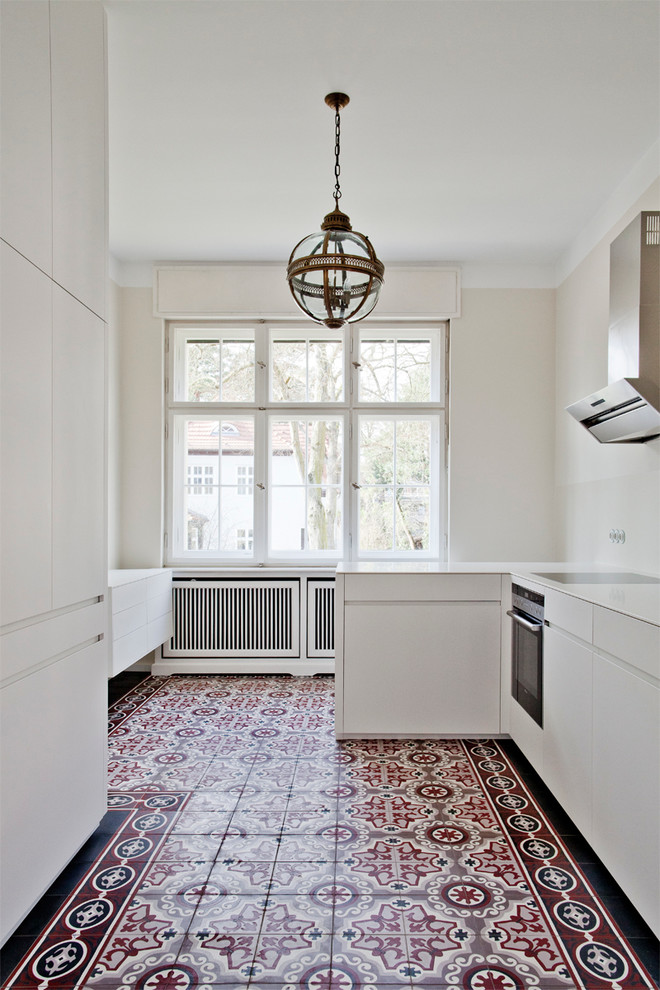 Cette photo montre une cuisine encastrable tendance fermée et de taille moyenne avec un placard à porte plane, des portes de placard blanches, une crédence blanche et une péninsule.