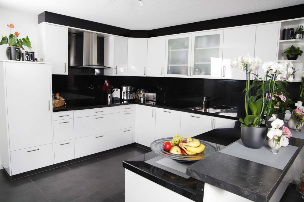 Idéer för stora funkis svart kök, med en integrerad diskho, luckor med glaspanel, vita skåp, granitbänkskiva, svart stänkskydd, rostfria vitvaror, klinkergolv i porslin och grått golv