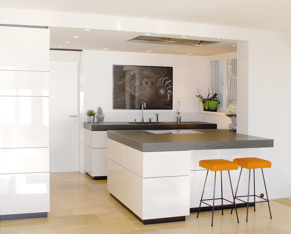 Example of a large minimalist galley limestone floor open concept kitchen design in Stuttgart with an undermount sink, flat-panel cabinets, white cabinets, marble countertops, white backsplash, stainless steel appliances and an island