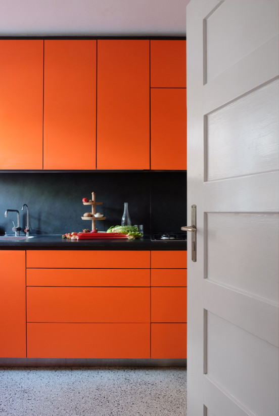 Foto de cocina lineal moderna cerrada con armarios con paneles lisos, puertas de armario naranjas y encimeras negras