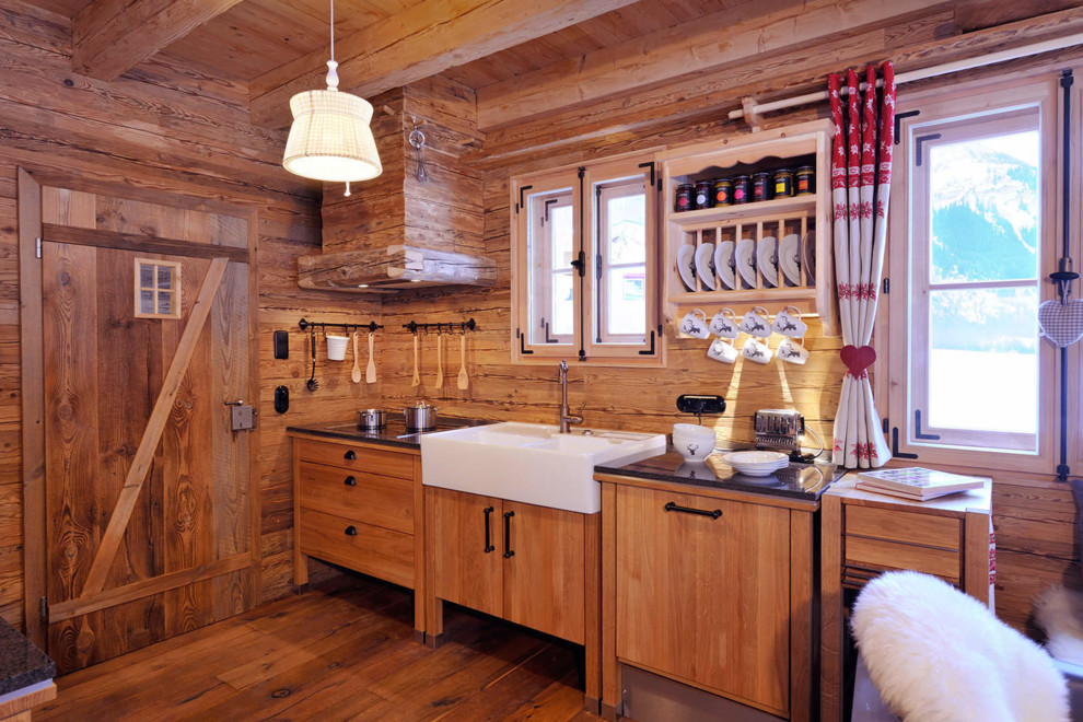 Einzeilige Rustikale Küche mit Landhausspüle, flächenbündigen Schrankfronten, hellen Holzschränken, Küchenrückwand in Beige und hellem Holzboden in Sonstige