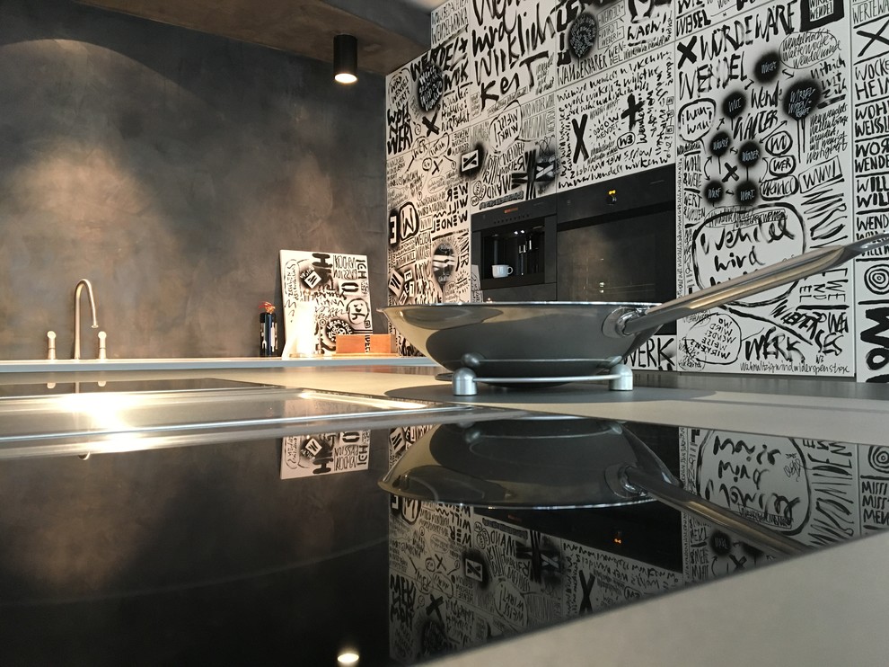 Inspiration for a small urban l-shaped open plan kitchen in Frankfurt with an island, a built-in sink, flat-panel cabinets, white cabinets, black splashback, black appliances, dark hardwood flooring and brown floors.
