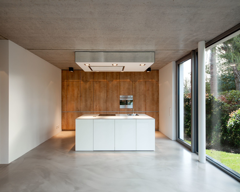 Bild på ett mellanstort funkis linjärt kök med öppen planlösning, med en nedsänkt diskho, släta luckor, rostfria vitvaror, en köksö, skåp i mellenmörkt trä, träbänkskiva och betonggolv