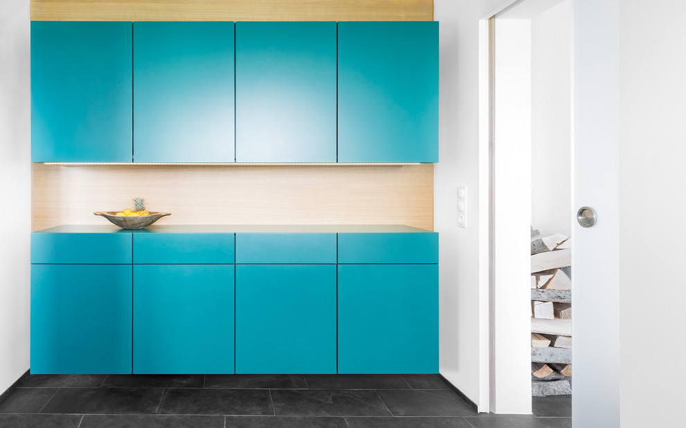 Modern kitchen in Stuttgart with flat-panel cabinets, blue cabinets, brown splashback, wood splashback and black floors.