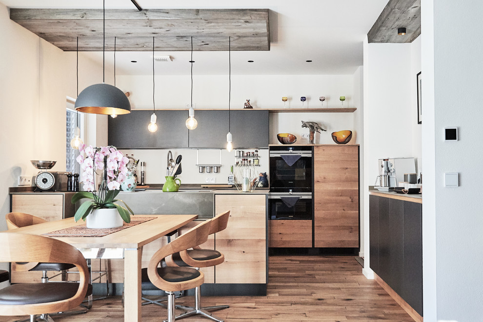 Idée de décoration pour une cuisine américaine parallèle design en bois brun de taille moyenne avec un évier encastré, un placard à porte plane, îlot et un plan de travail gris.